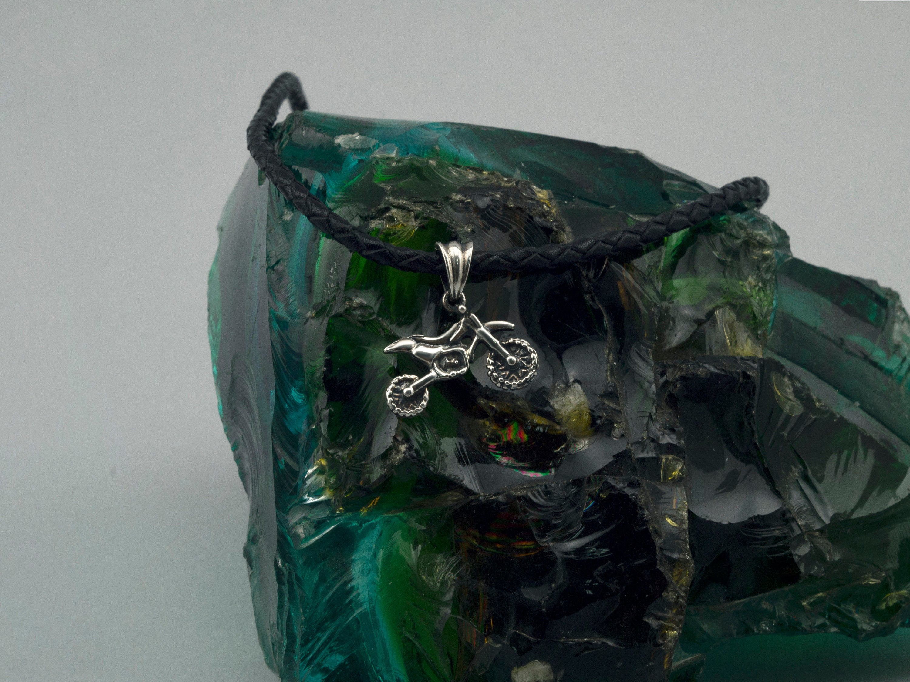 Silver enduro dirt bike pendant hanging on a black cord, front view