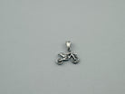 Small sterling silver motocross pendant lying flat on a light background