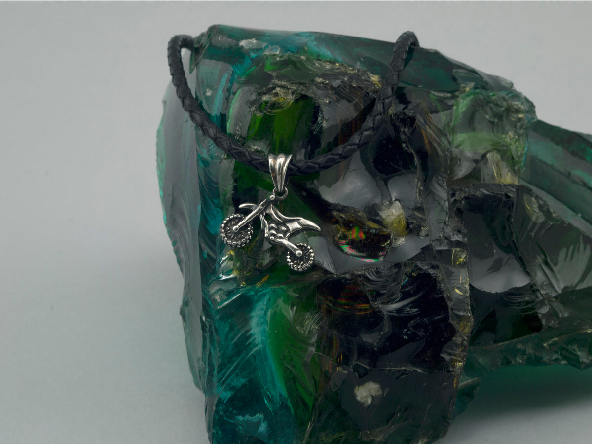 Enduro motorcycle pendant on a cord, angled view of the oxidized bike frame