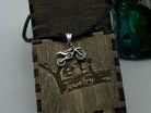 Enduro motorcycle sterling silver pendant on a black cord against a wooden Yeti box