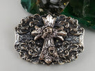 Close-up of the sculpted cross and skulls on the heavy belt buckle