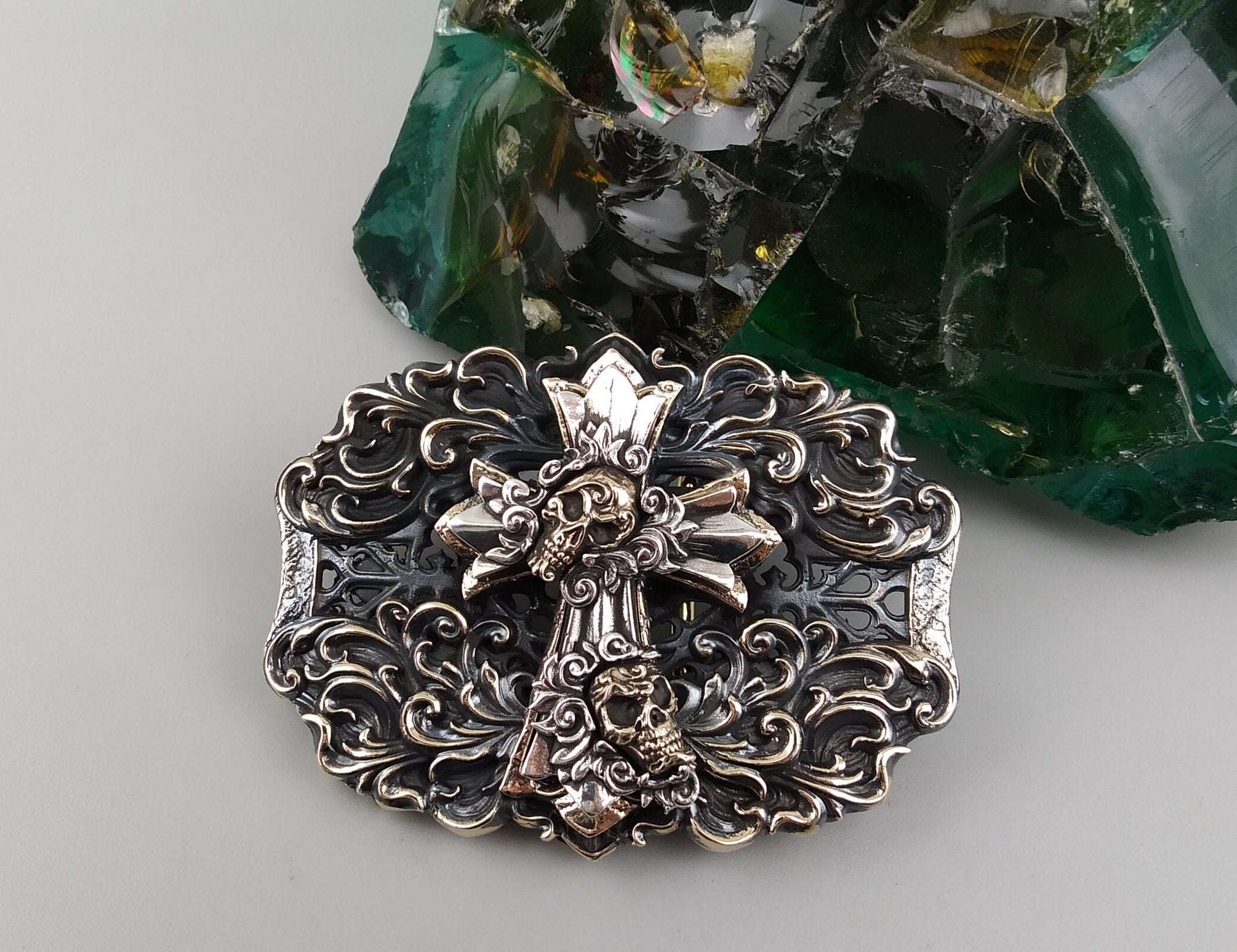 Gothic cross belt buckle front view with skull relief and brass details