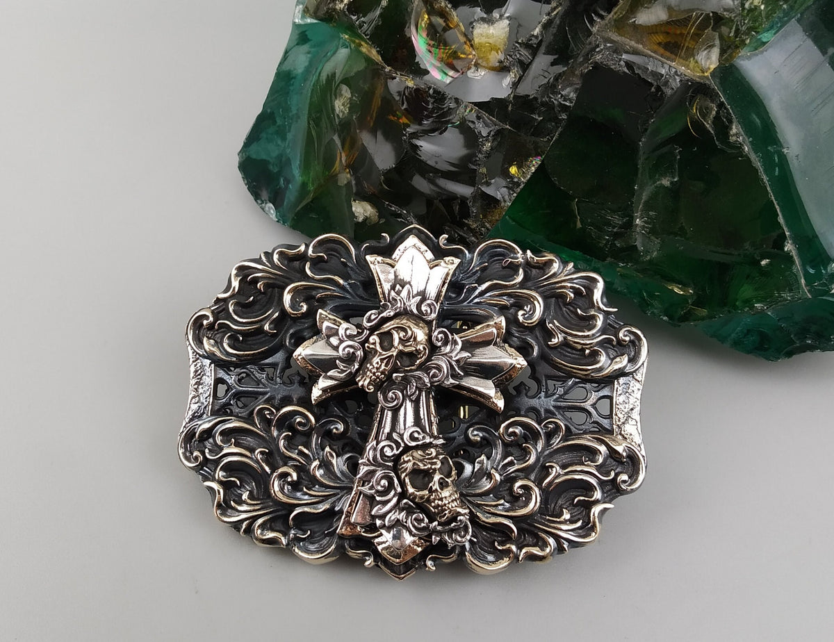Gothic cross belt buckle front view with skull relief and brass details