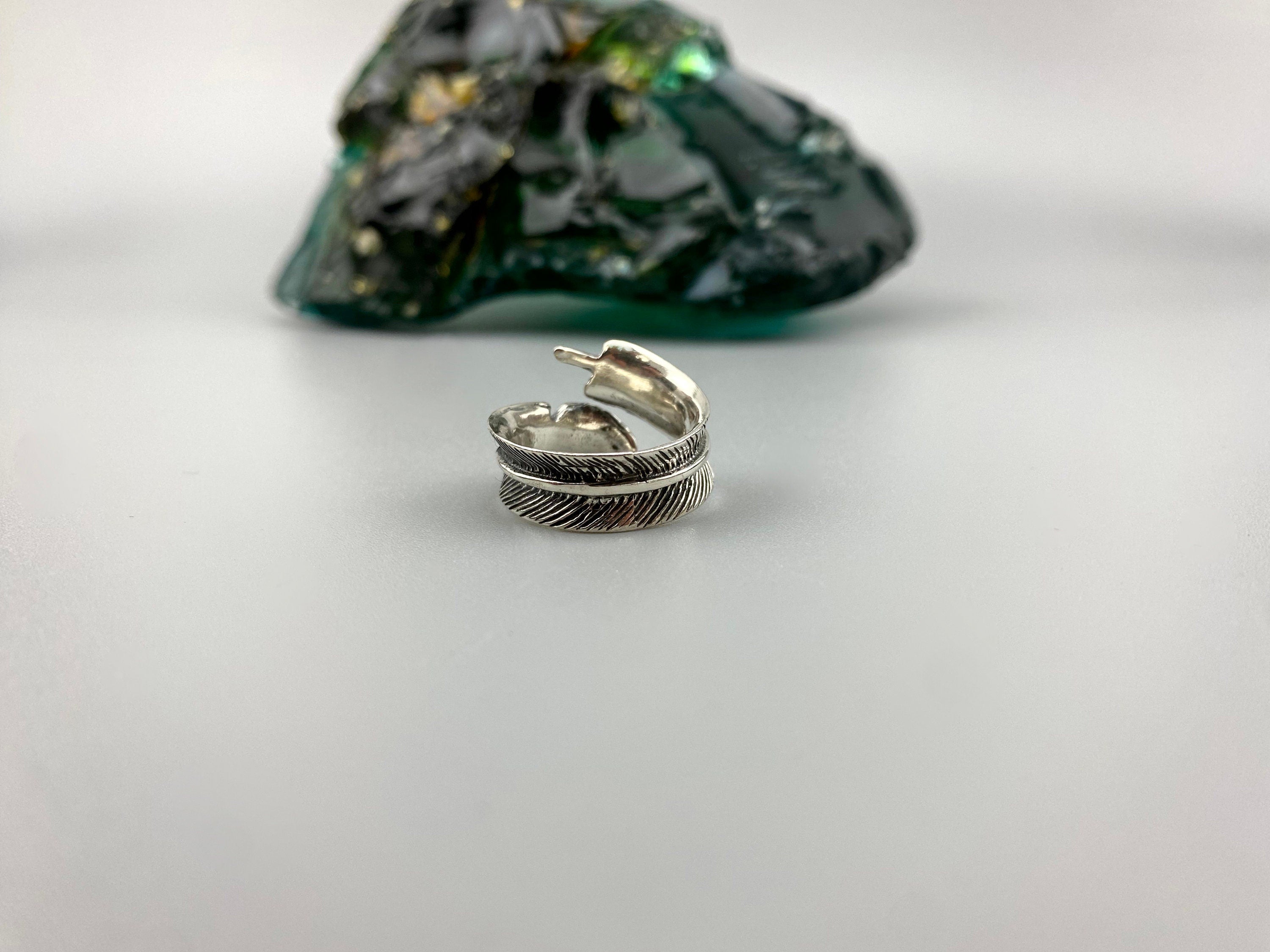 Adjustable feather ring lying on its side, textured feather detail