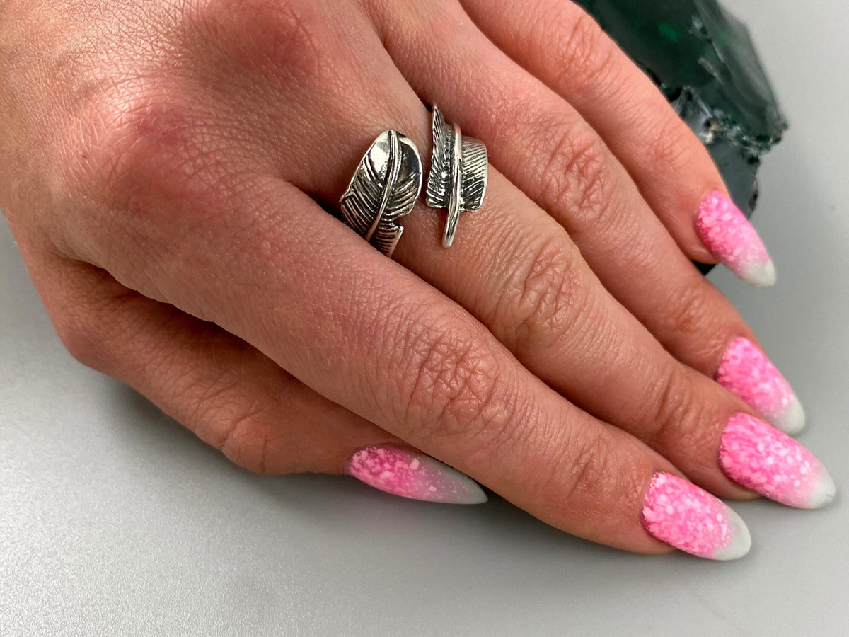 Silver feather bypass ring worn on the middle finger