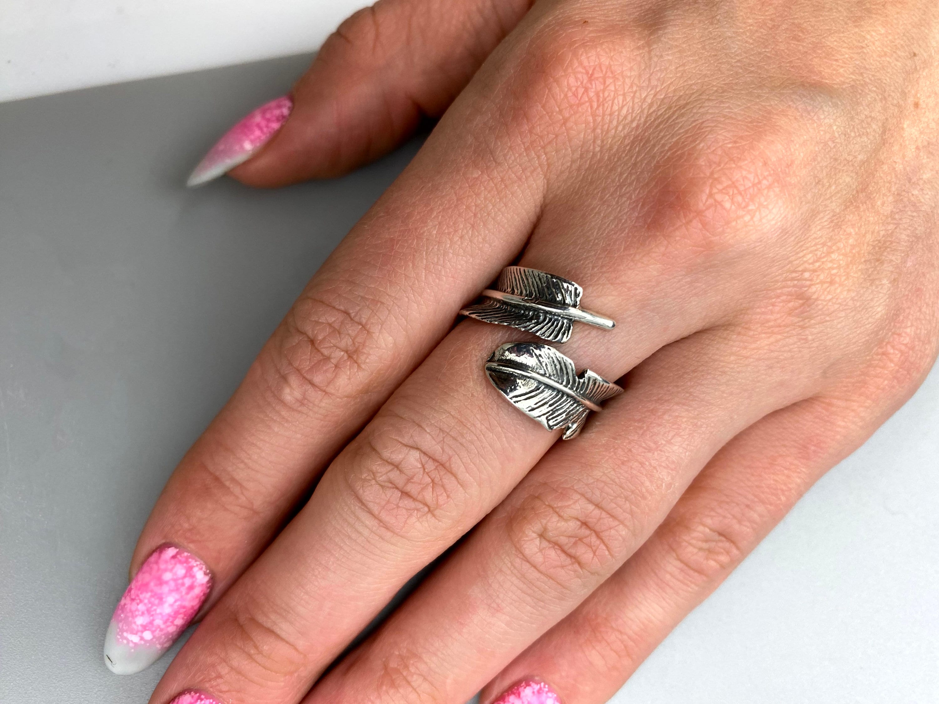 Feather sterling silver ring on a woman's hand with pink manicure