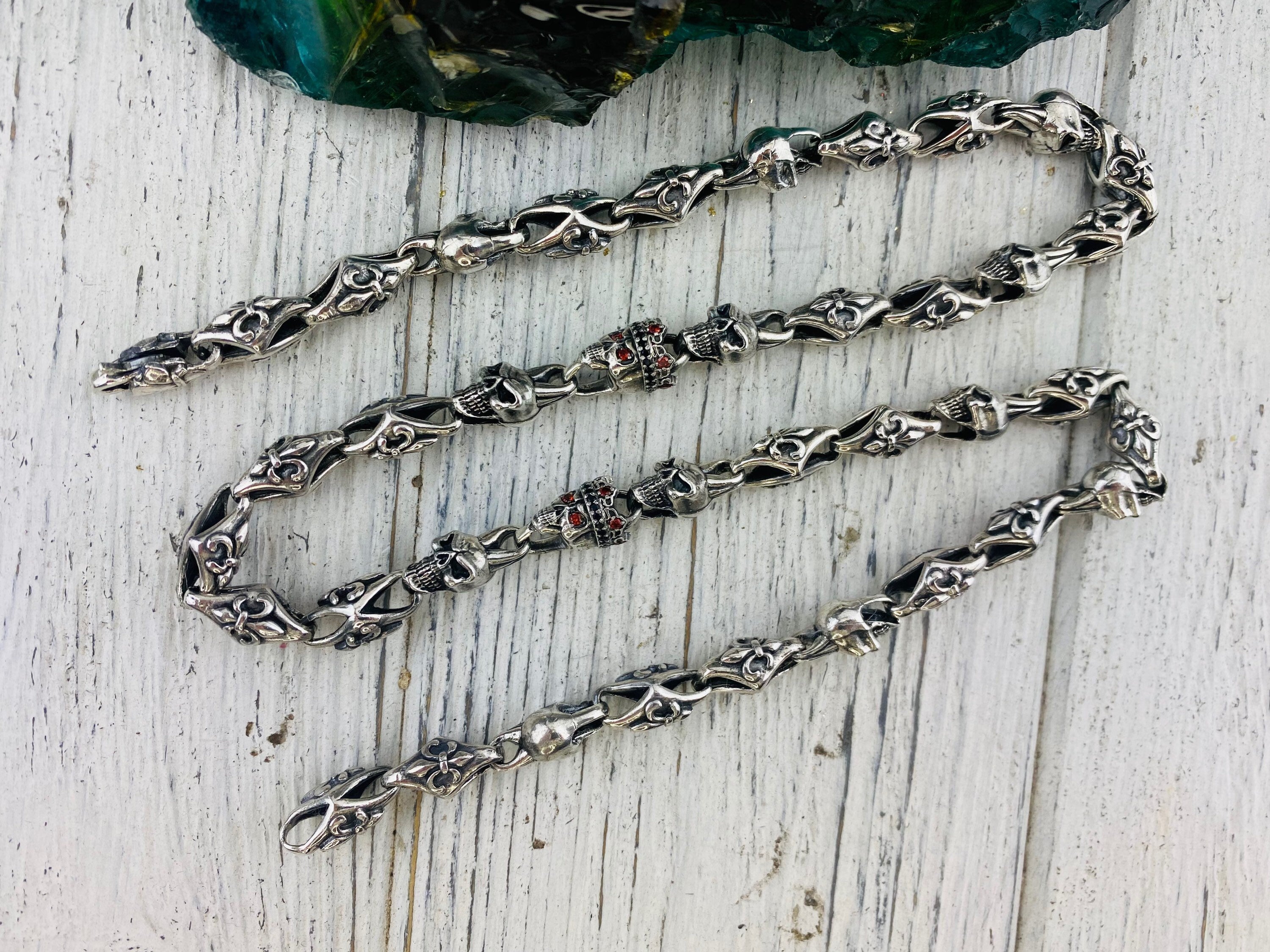 Fleur de lis skull chain laid straight, showing alternating links