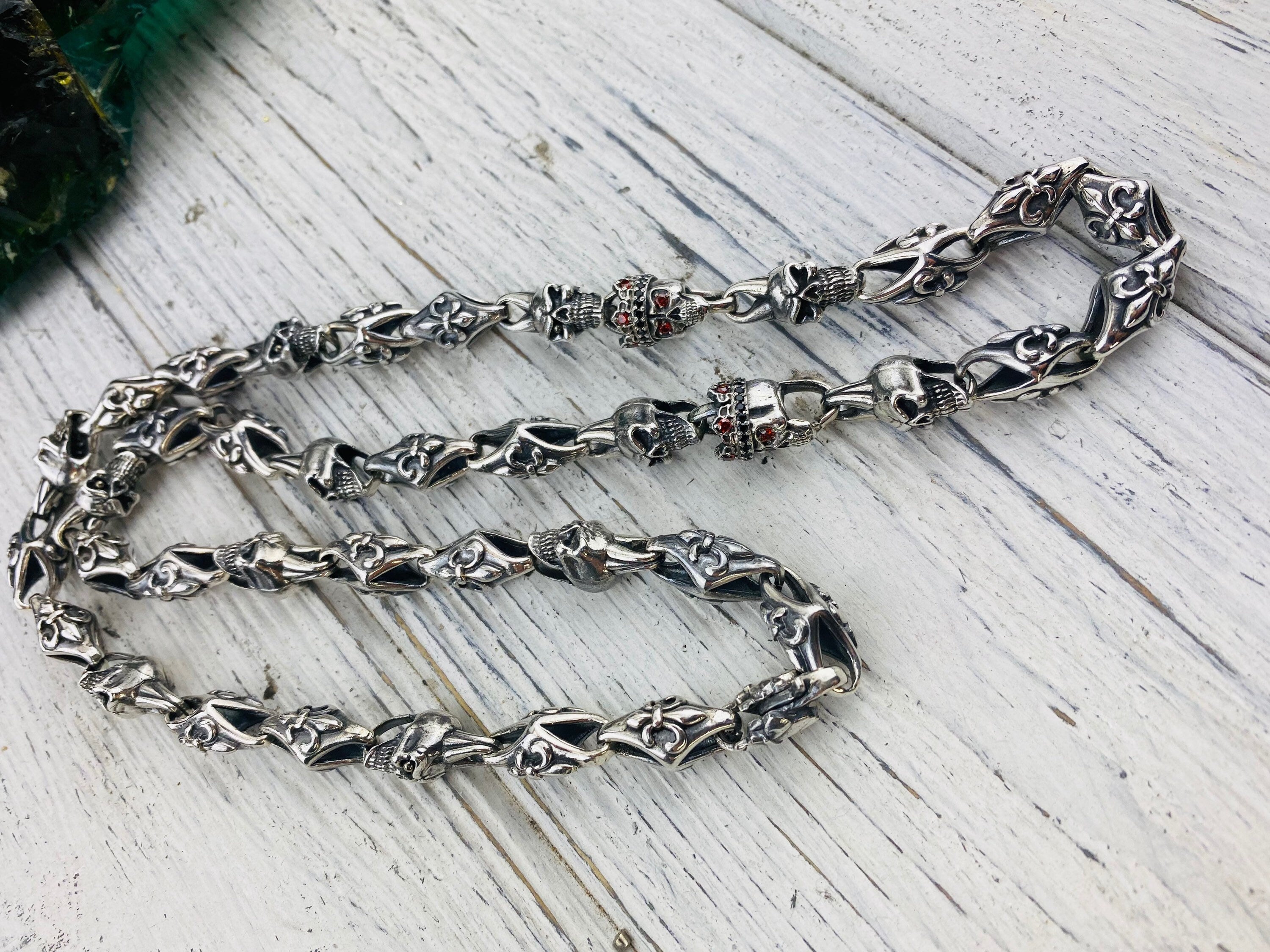 Detail of oxidized crowned skull links on the fleur de lis chain