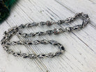 Detail of oxidized crowned skull links on the fleur de lis chain