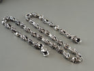 Fleur de lis crowned skull silver chain coiled with the clasp, on grey
