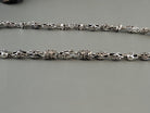 Close-up of the skull and fleur de lis links of the silver chain