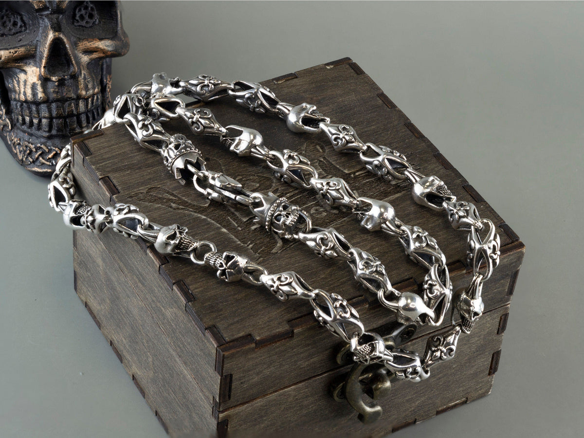 Fleur de lis crowned skull silver chain draped over a wooden box