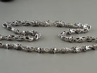 Fleur de lis crowned skull chain laid in two rows on grey