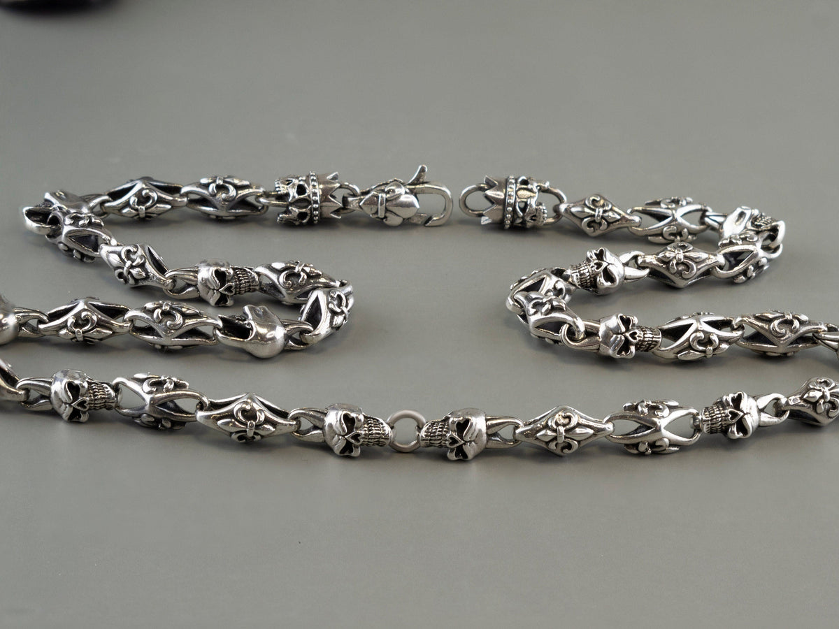Fleur de lis crowned skull chain laid in two rows on grey