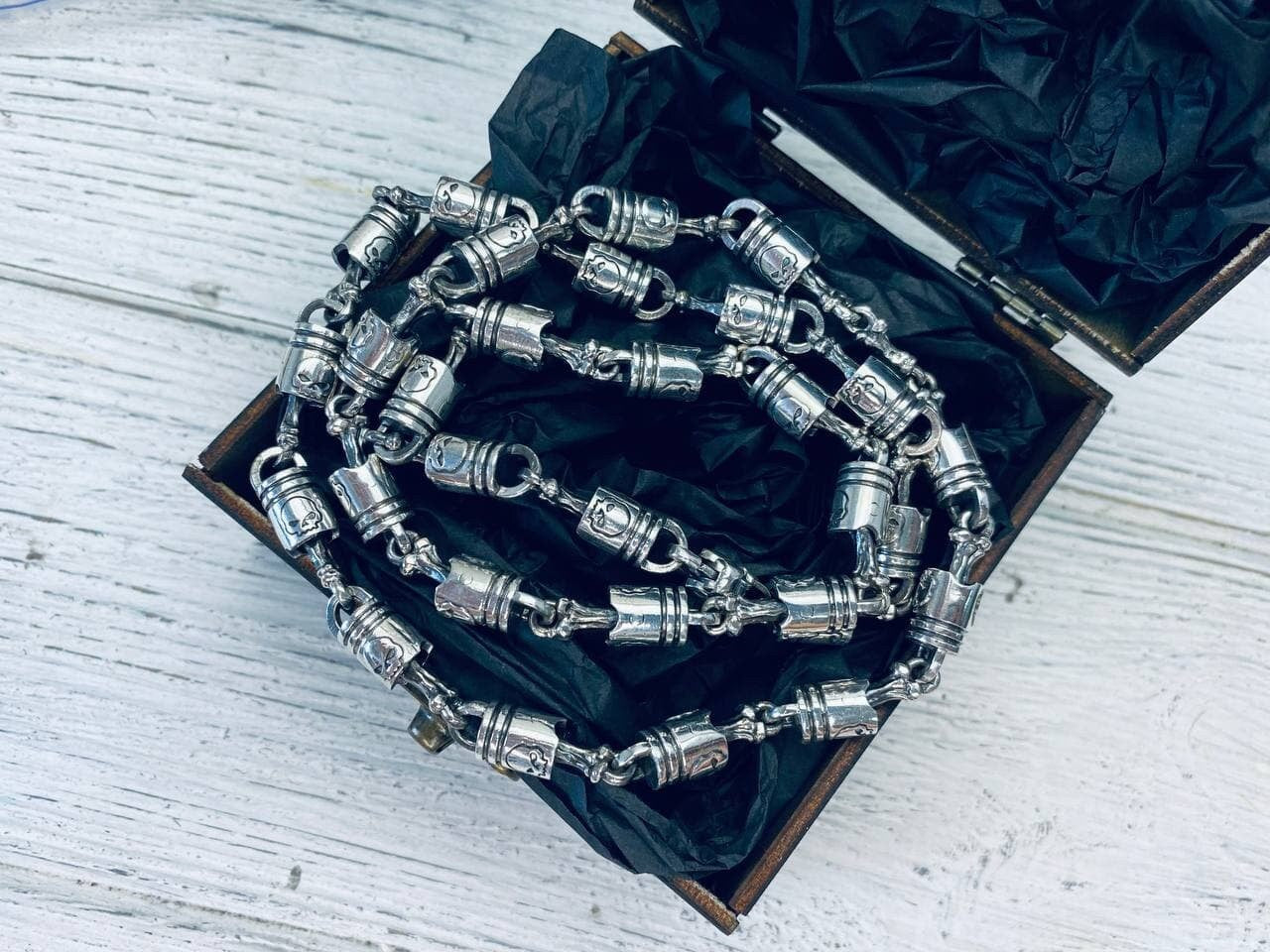 Forcer heavy silver chain inside an open wooden gift box