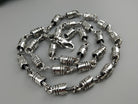 Forcer silver chain coiled on a light background, full view of the barrel links