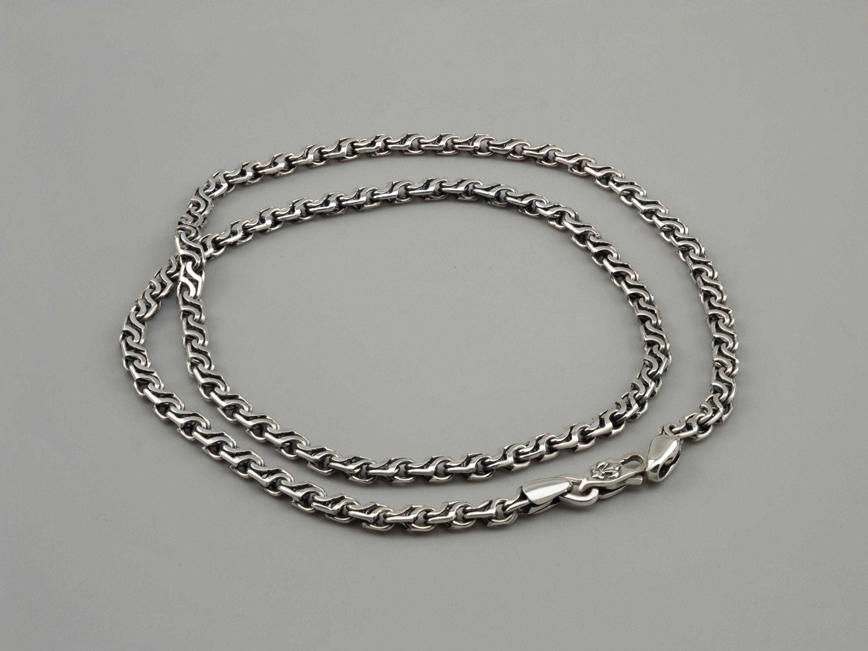 Forge sterling silver chain laid flat in an oval, showing the lobster clasp
