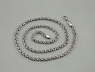 Forge sterling silver chain coiled in a spiral on a gray background