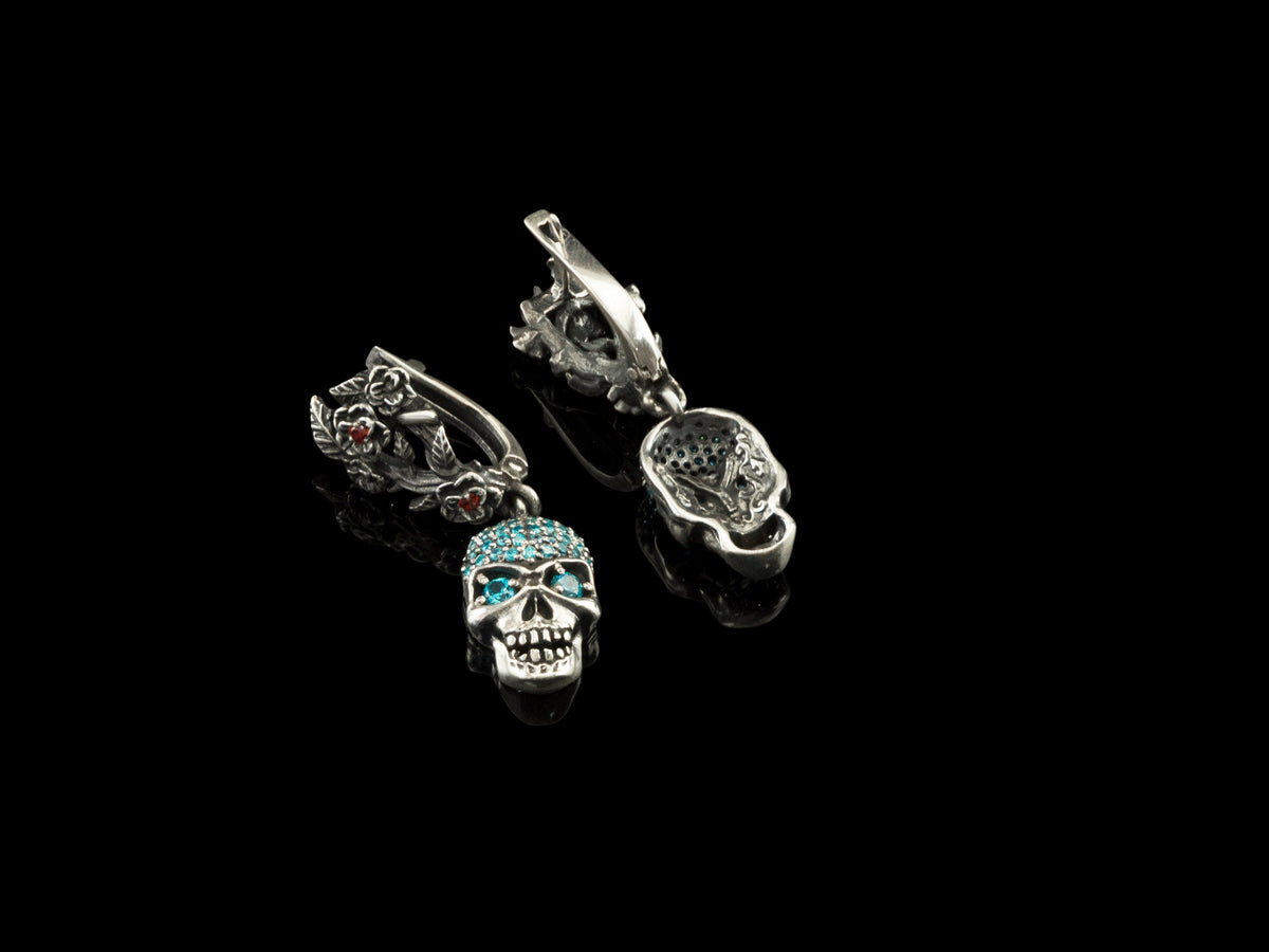 Frida Light blue CZ skull earrings with one floral leverback open, on black