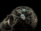 Frida Light blue pave skull earrings displayed on a carved skull