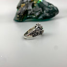 Women's silver skull ring lying on its side, skull detail