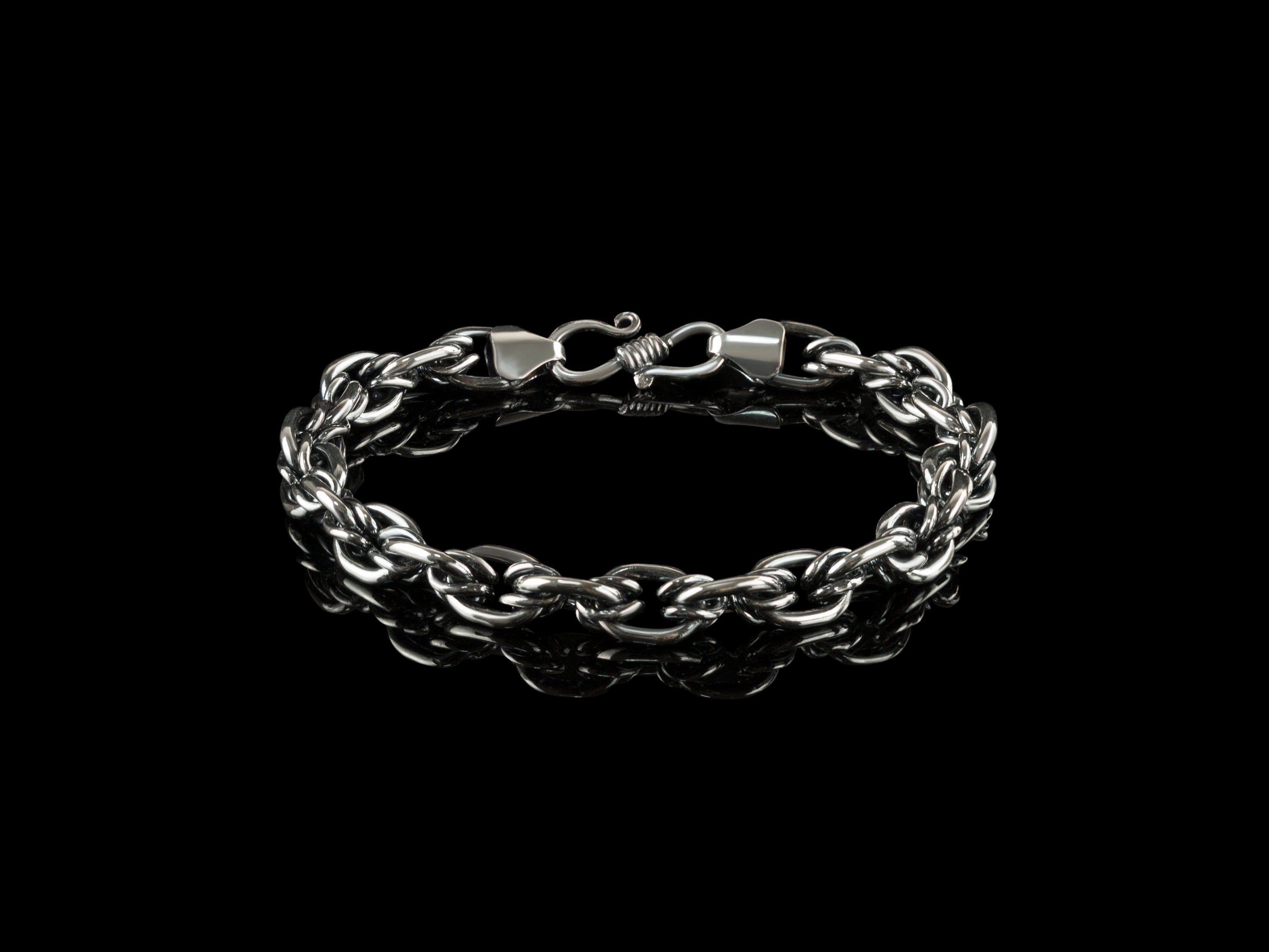 Graf men's silver chain bracelet laid in a circle on black