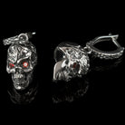 Headhunter earrings lying flat, cracked skull texture and red stones