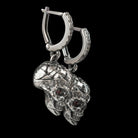 Close-up of a battle-worn silver skull earring hanging from its patterned hoop
