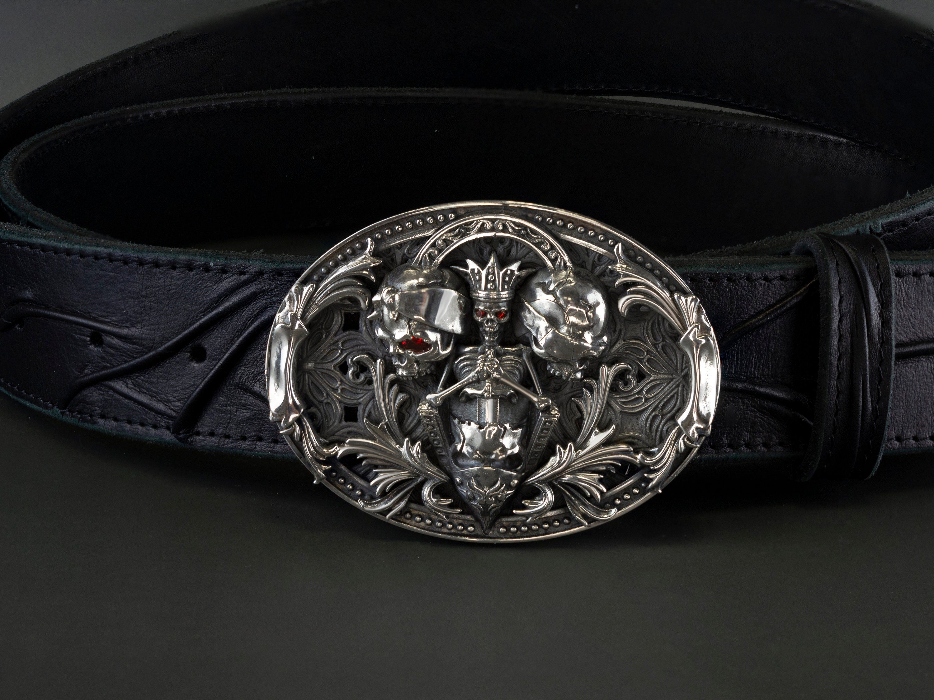 Oval silver skull belt buckle with ornamental scrollwork, front view