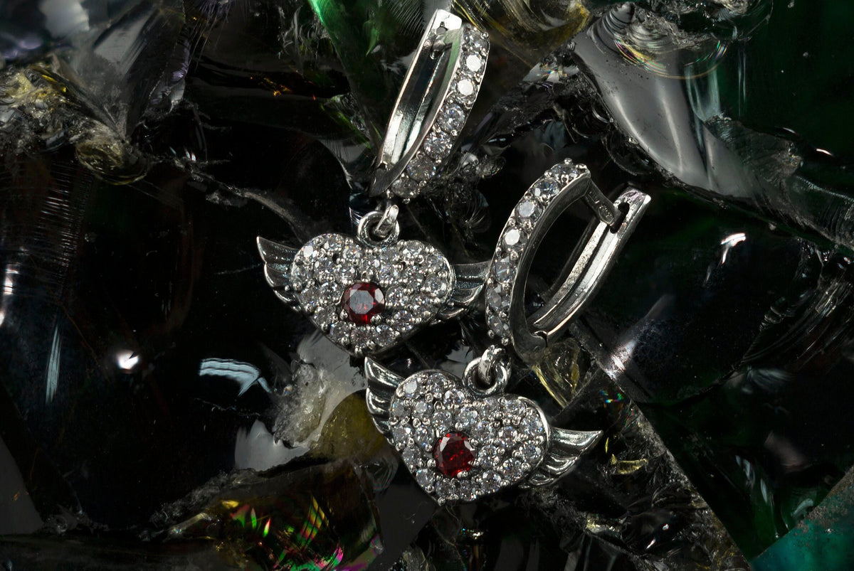 Winged heart earrings in 925 sterling silver with red cubic zirconia center stones and clear CZ accents