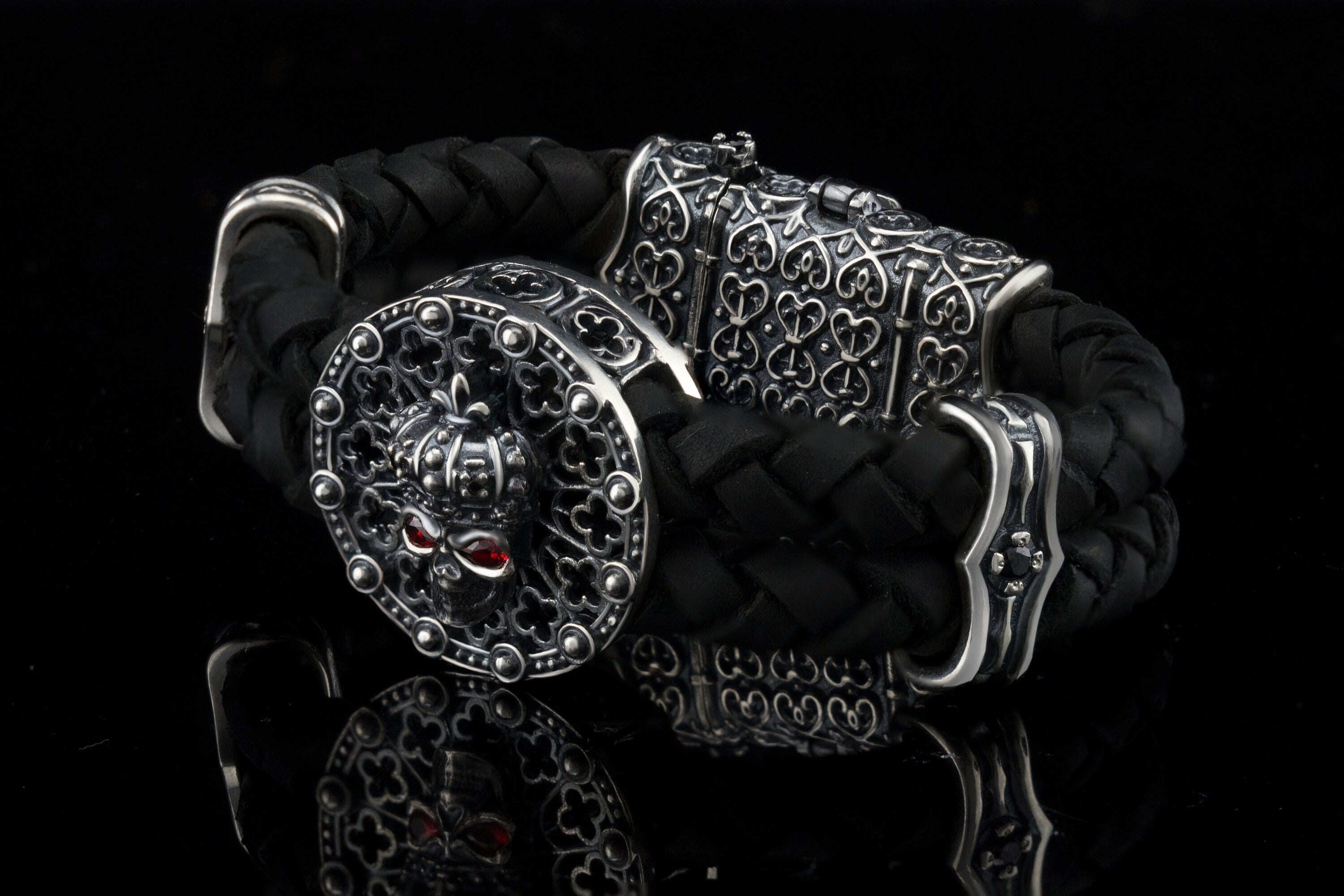 Crowned skull bracelet with 925 sterling silver details, genuine black braided leather and red cubic zirconia eyes