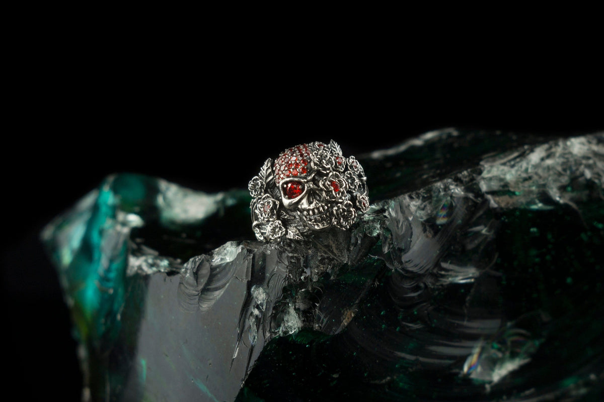 Handcrafted 925 sterling silver "Frida" skull ring wrapped in roses with sparkling crimson red cubic zirconia pave on a dark background