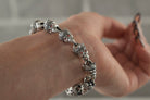 Santa Muerte bracelet in 925 sterling silver featuring linked crowned skulls and red stone accents by Yeti Jewelry