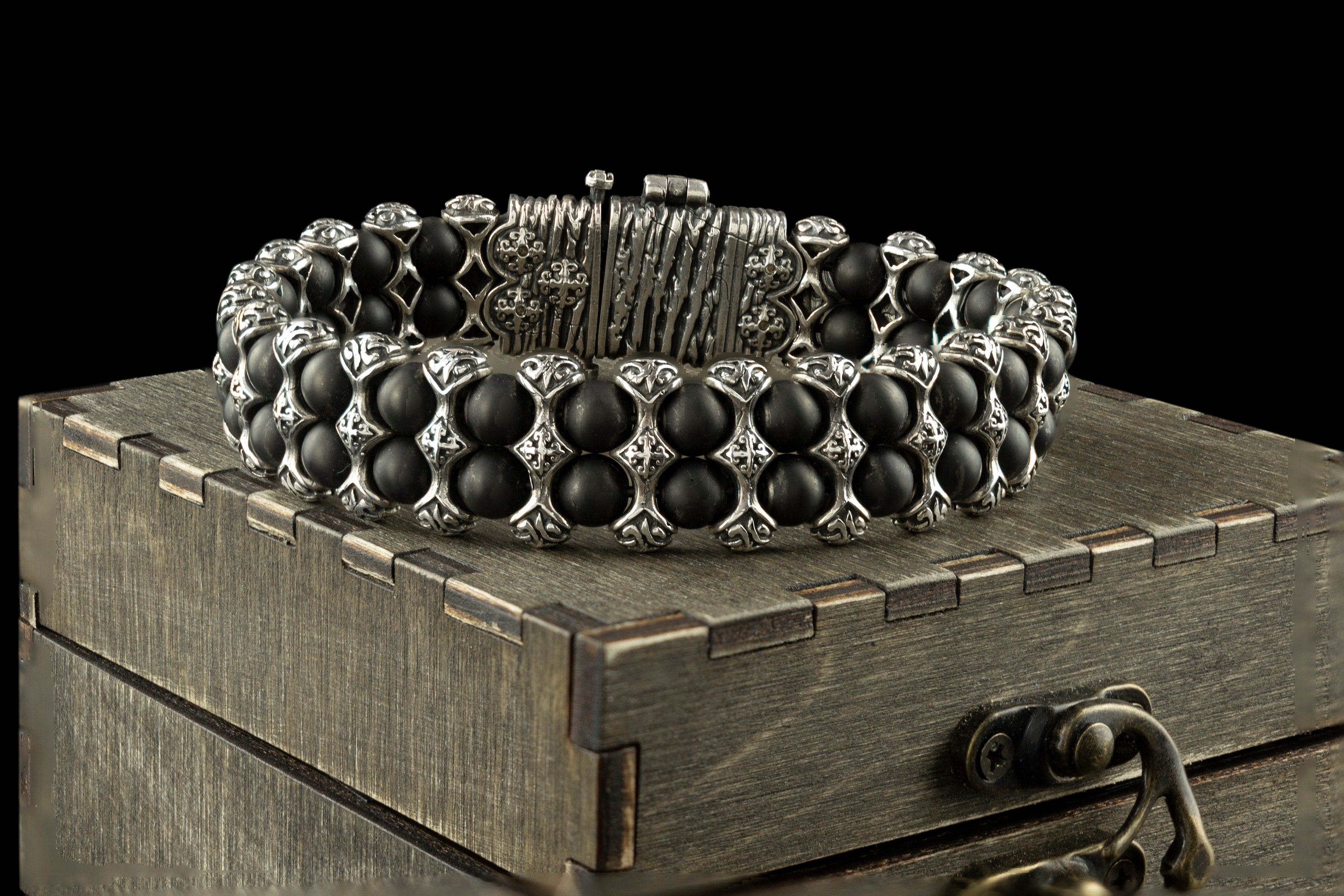 The Saint Victor bracelet by Yeti Jewelry features polished black onyx beads, intricately detailed sterling silver elements, and a prominent decorative central motif. This approximately 75-gram statement bracelet is handcrafted in 925 sterling silver and can be custom-made to the requested wrist size.