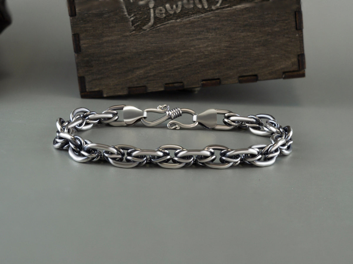 Heavy 925 sterling silver chain bracelet with polished interlocking links and a decorative clasp, displayed on a gray background beside a Yeti Jewelry wooden box.