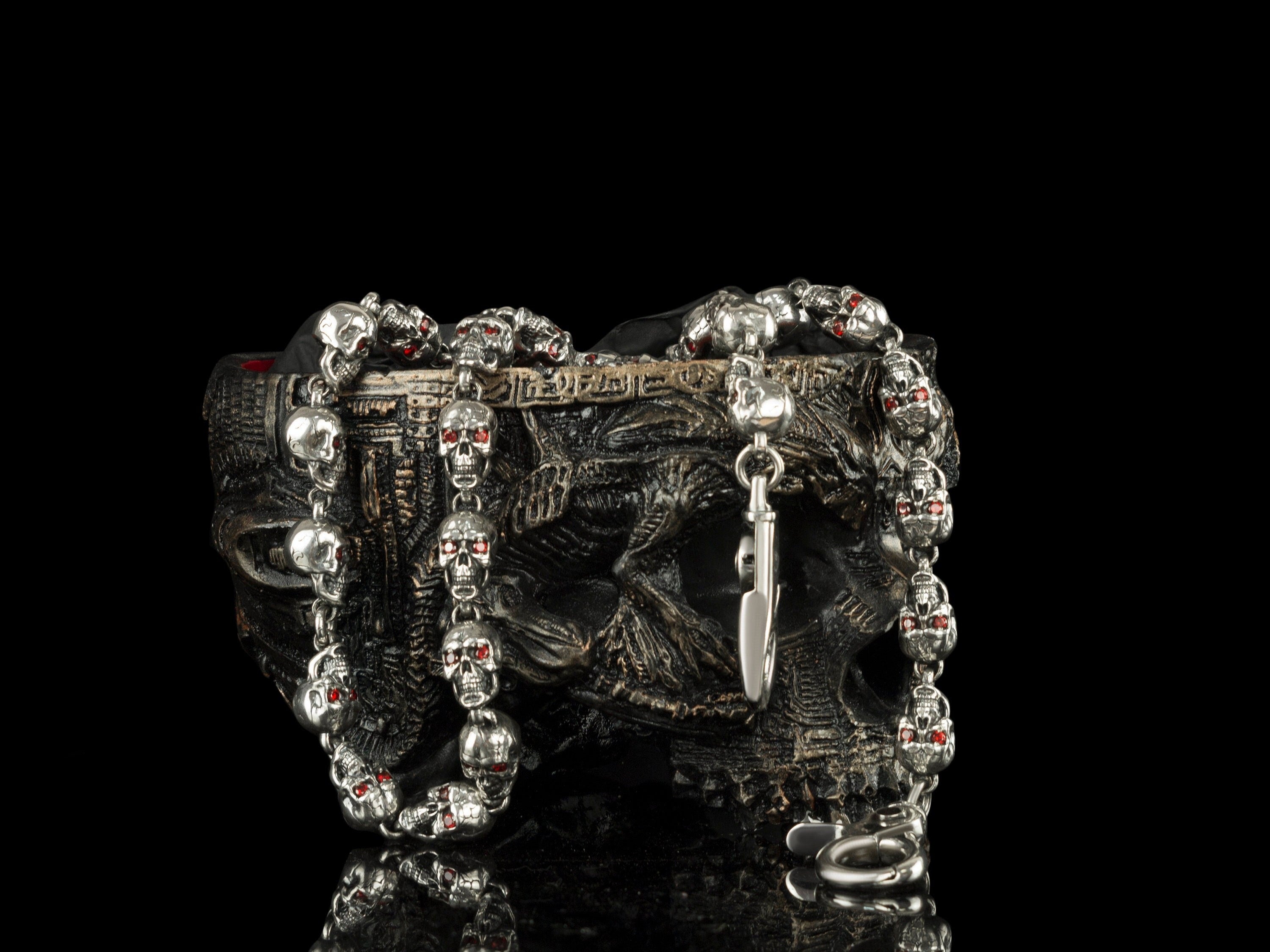 Handcrafted 170g solid sterling silver "Mitchell" wallet chain featuring linked skulls with glowing red cubic zirconia eyes on a dark skull display