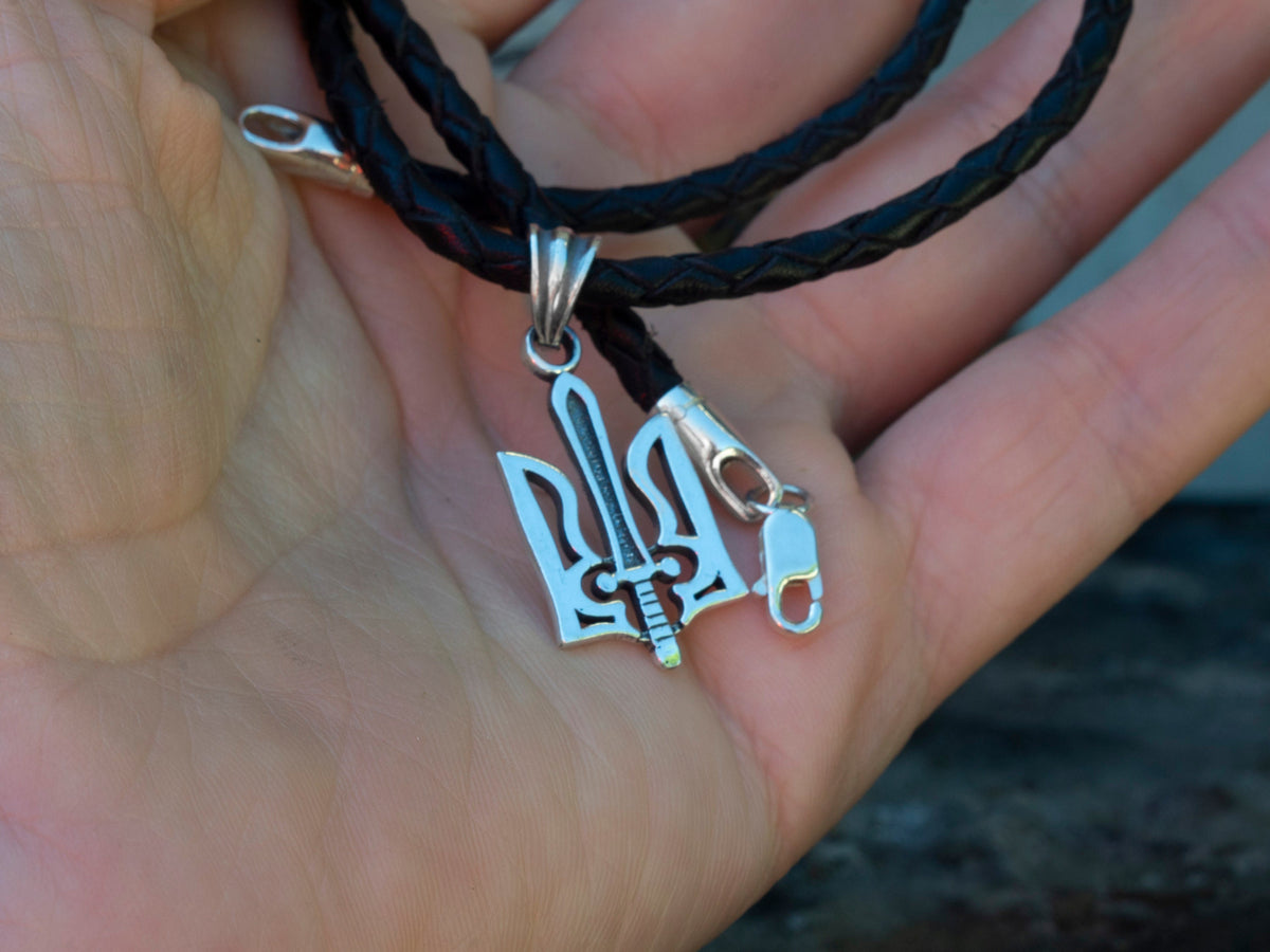 Ukrainian Tryzub pendant in 925 sterling silver with a decorative sword motif, displayed on a black cord by Yeti Jewelry