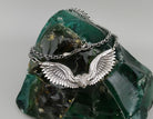 Angelisa sterling silver angel wings necklace with intricately sculpted feathers and an ornate central detail, displayed on a dark green decorative stone.
