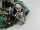 Vigor V-Twin skull pendant in 925 sterling silver with an ornamental fleur-de-lis-inspired emblem and sculpted mechanical details, photographed with a silver biker chain.