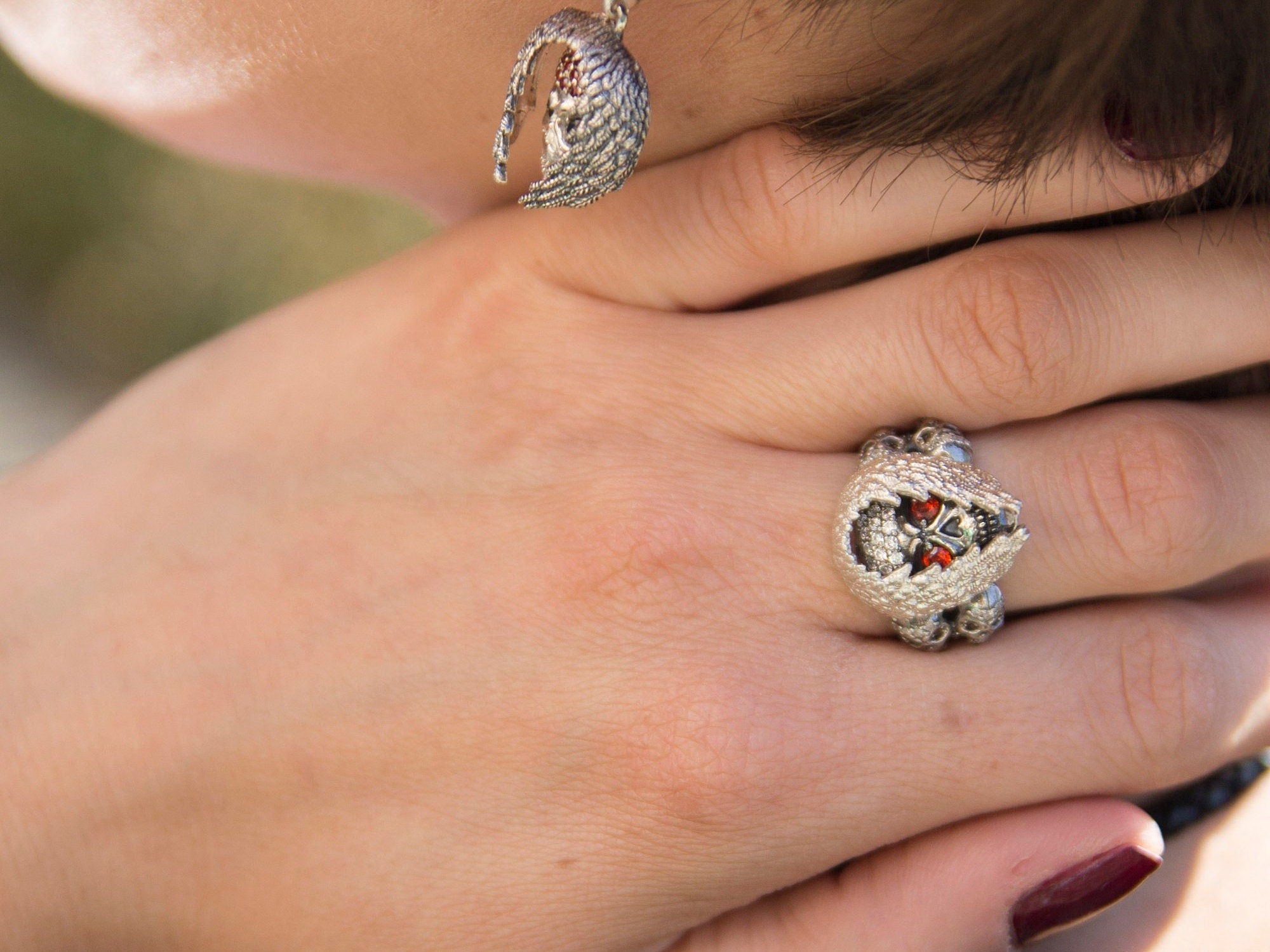 Anabel women's skull ring in 925 sterling silver with red cubic zirconia eyes and intricate feather-like silver detailing by Yeti Jewelry