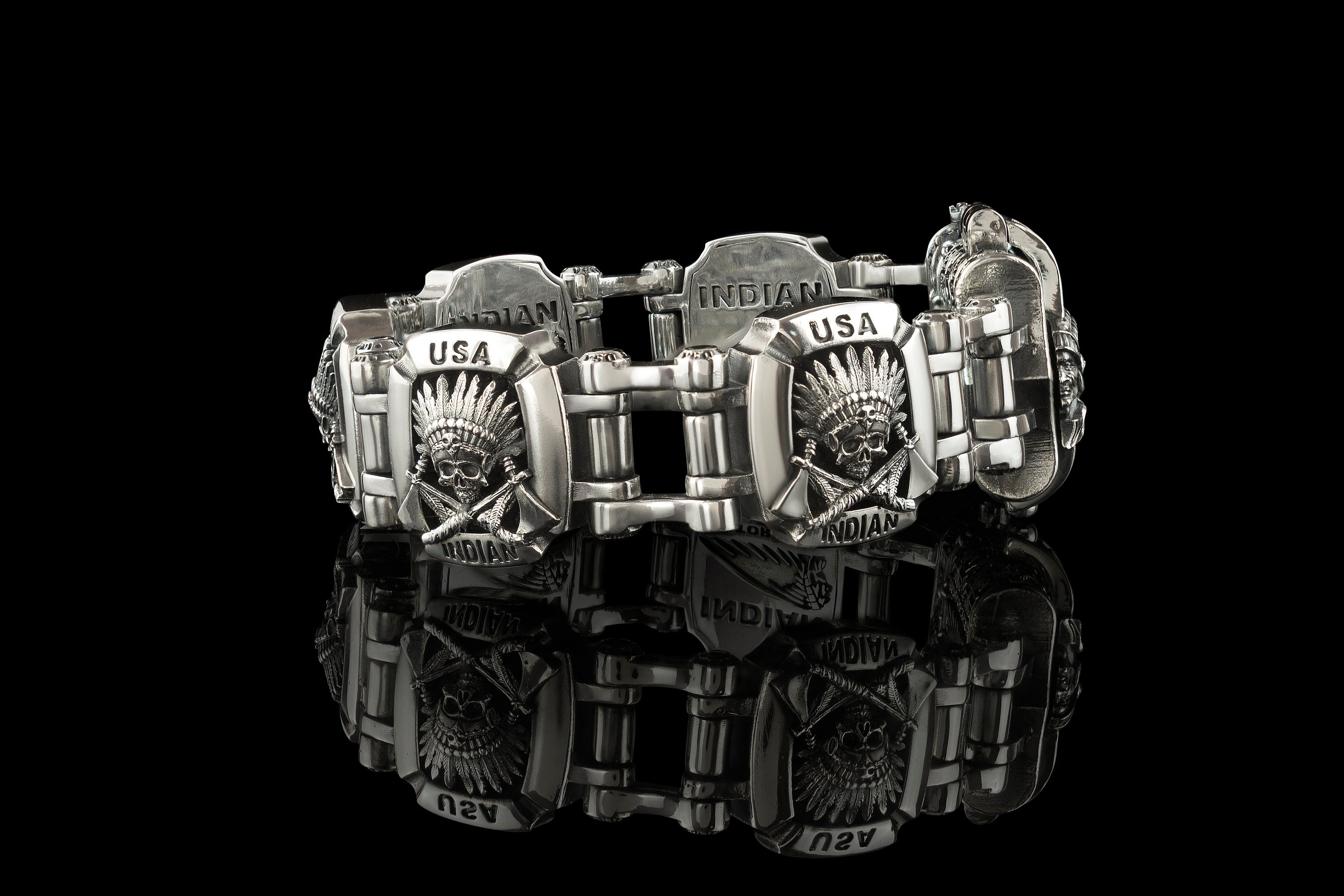 Indian bracelet laid out on black, linked silver plates with geometric pattern