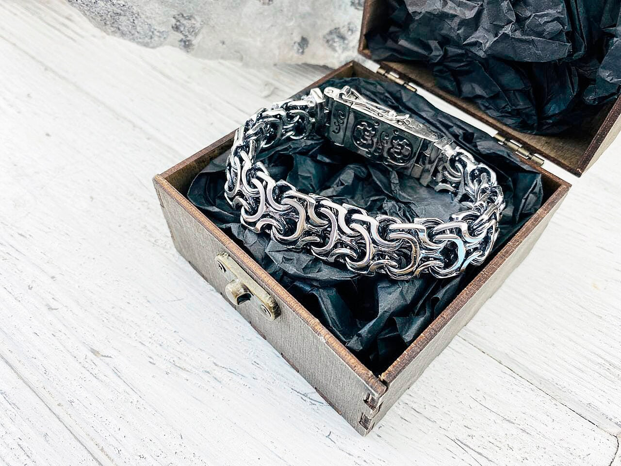 Heavy interlocking link bracelet resting in an open wooden gift box
