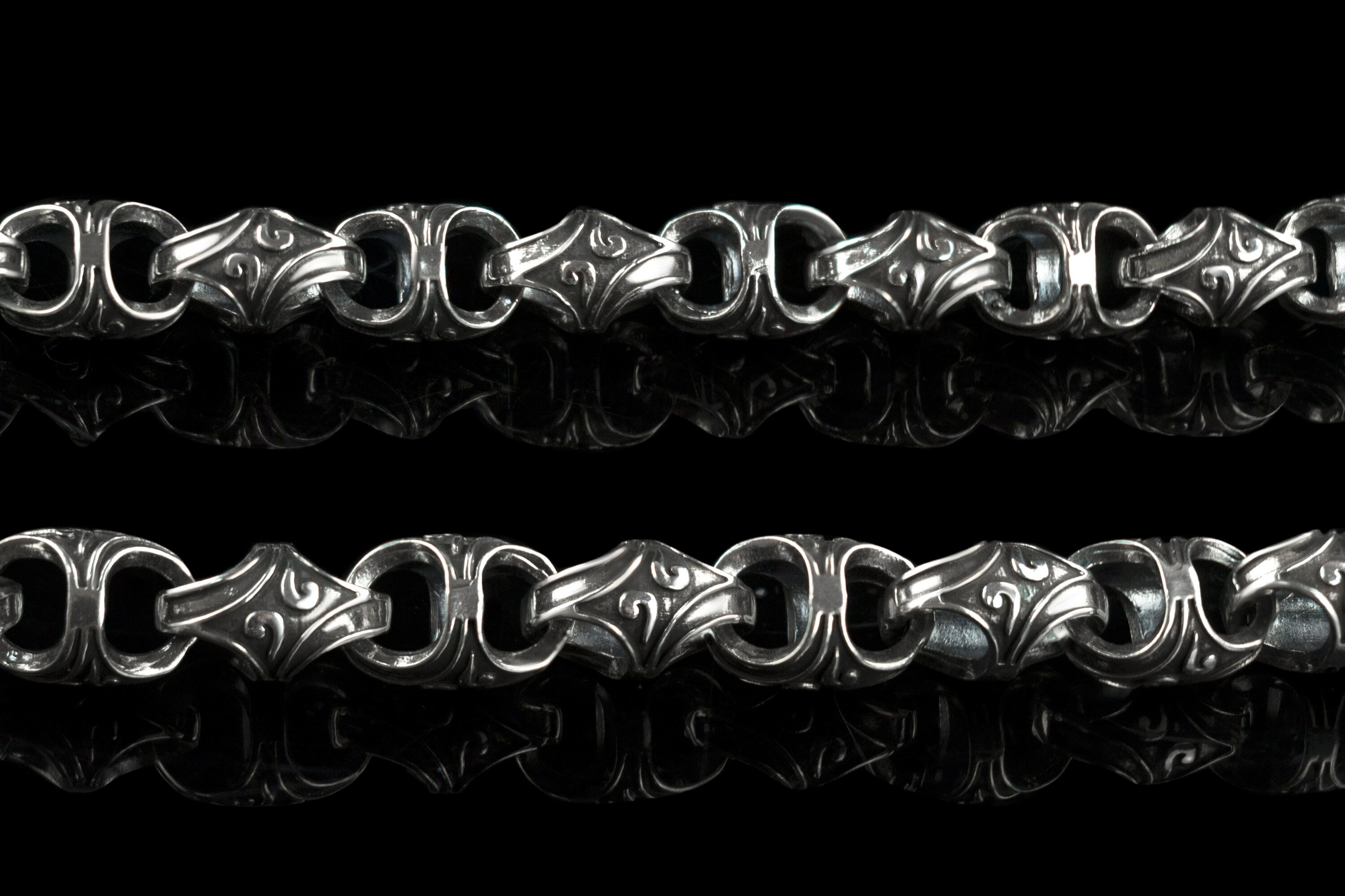 Close-up of Mokorr chain links with sculpted oxidized ornament and polished edges