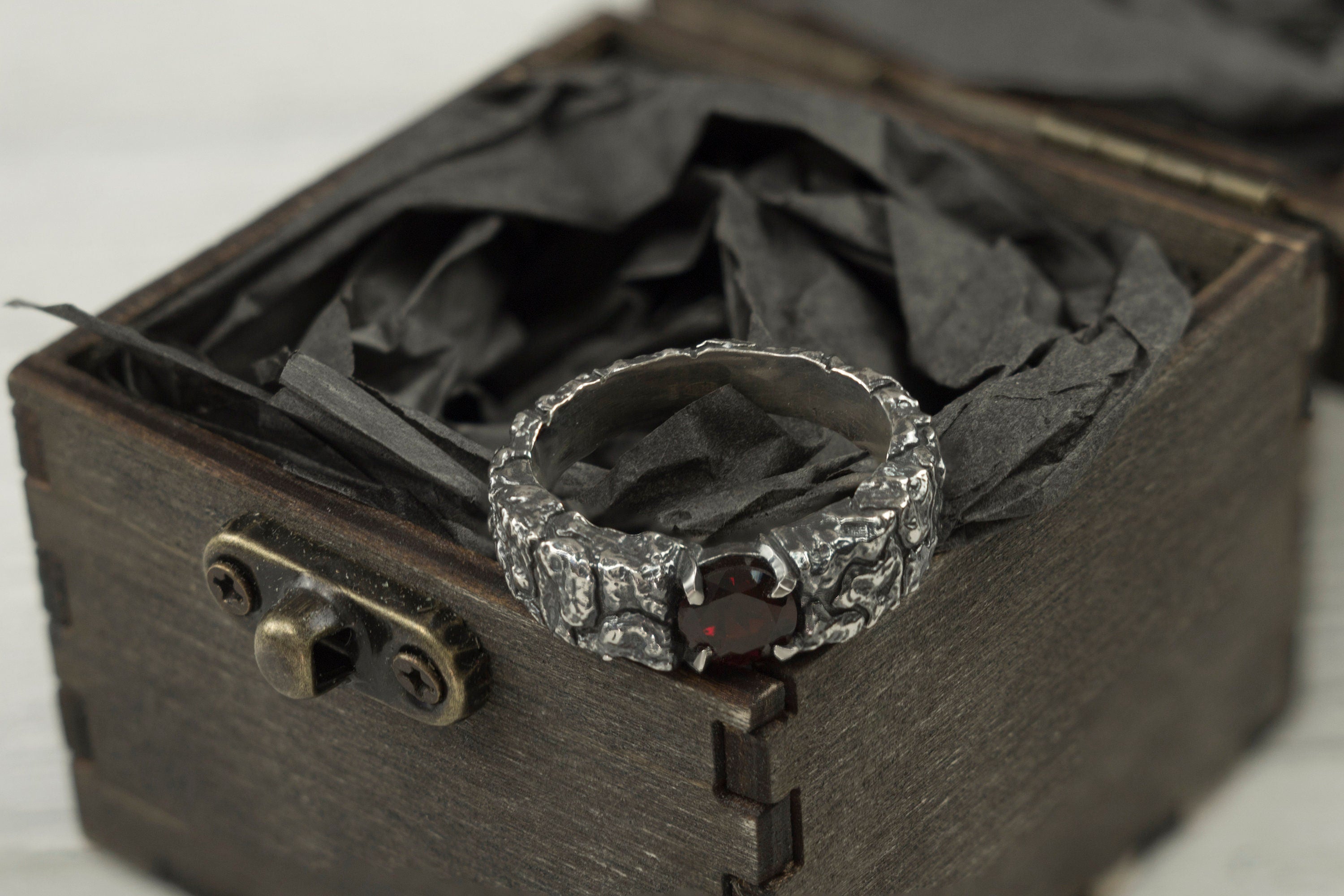 Mons Igneus ring standing in an open gift box, band and garnet