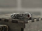 Textured silver garnet ring standing on a box, three-quarter view