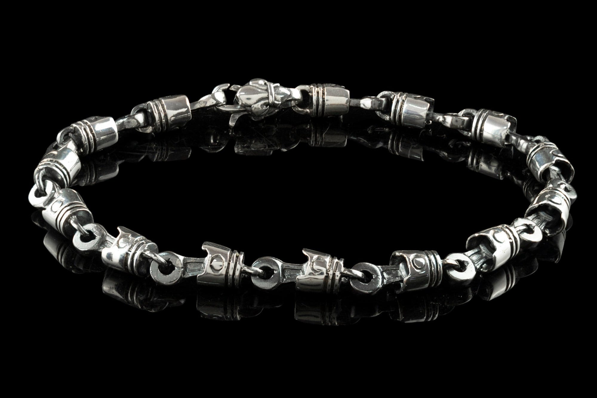 Men's silver piston bracelet laid flat, showing lobster clasp and piston links