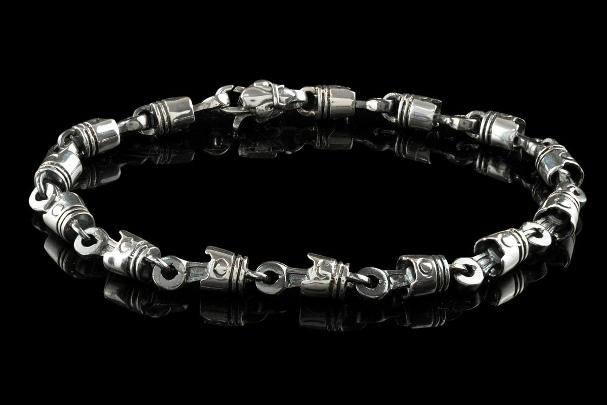 Men's silver piston bracelet laid flat, showing lobster clasp and piston links