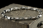 Piston and rod silver bracelet across a wooden box lid, side angle