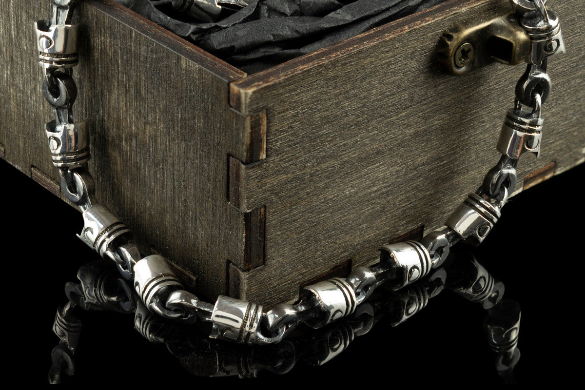 Close-up of oxidized silver piston links and connecting rods on a box corner