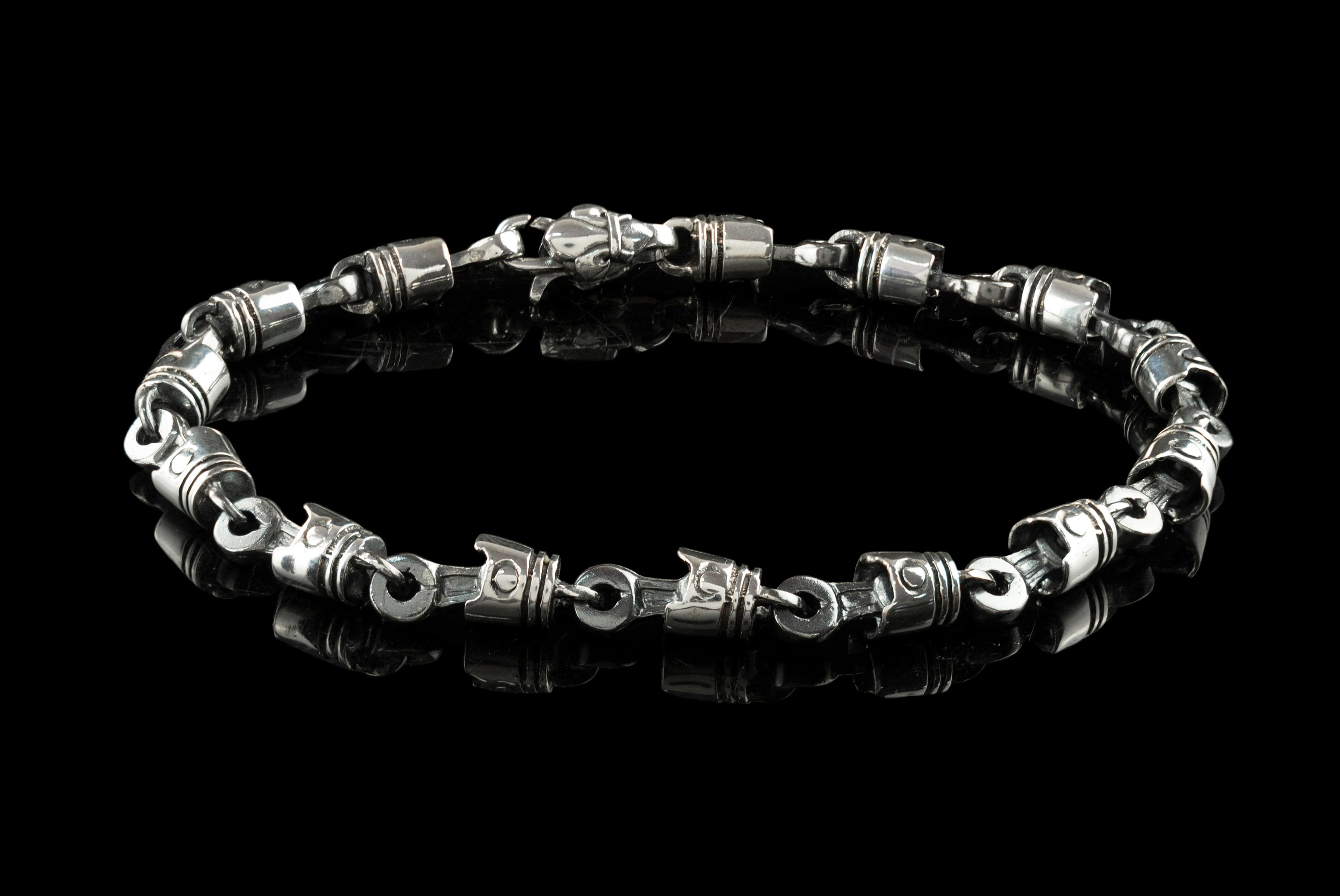 Full view of the piston and rod bracelet with lobster clasp on black background